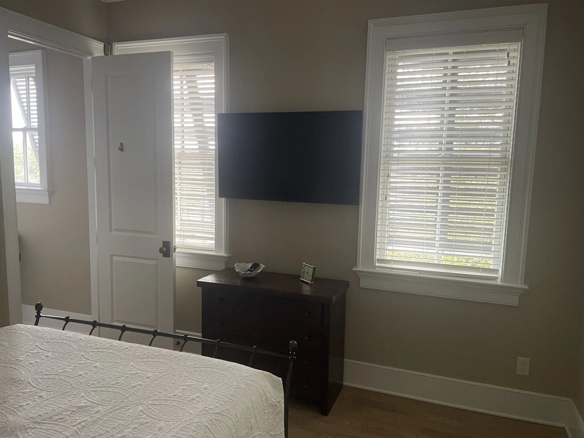 Guest bedroom with iron frame queen bed, white bedding, and navy accent pillows