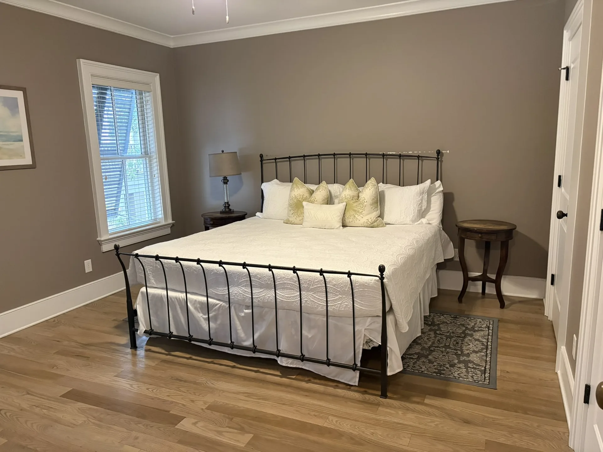 Master bedroom with king iron frame bed, warm gray walls, and seascape art