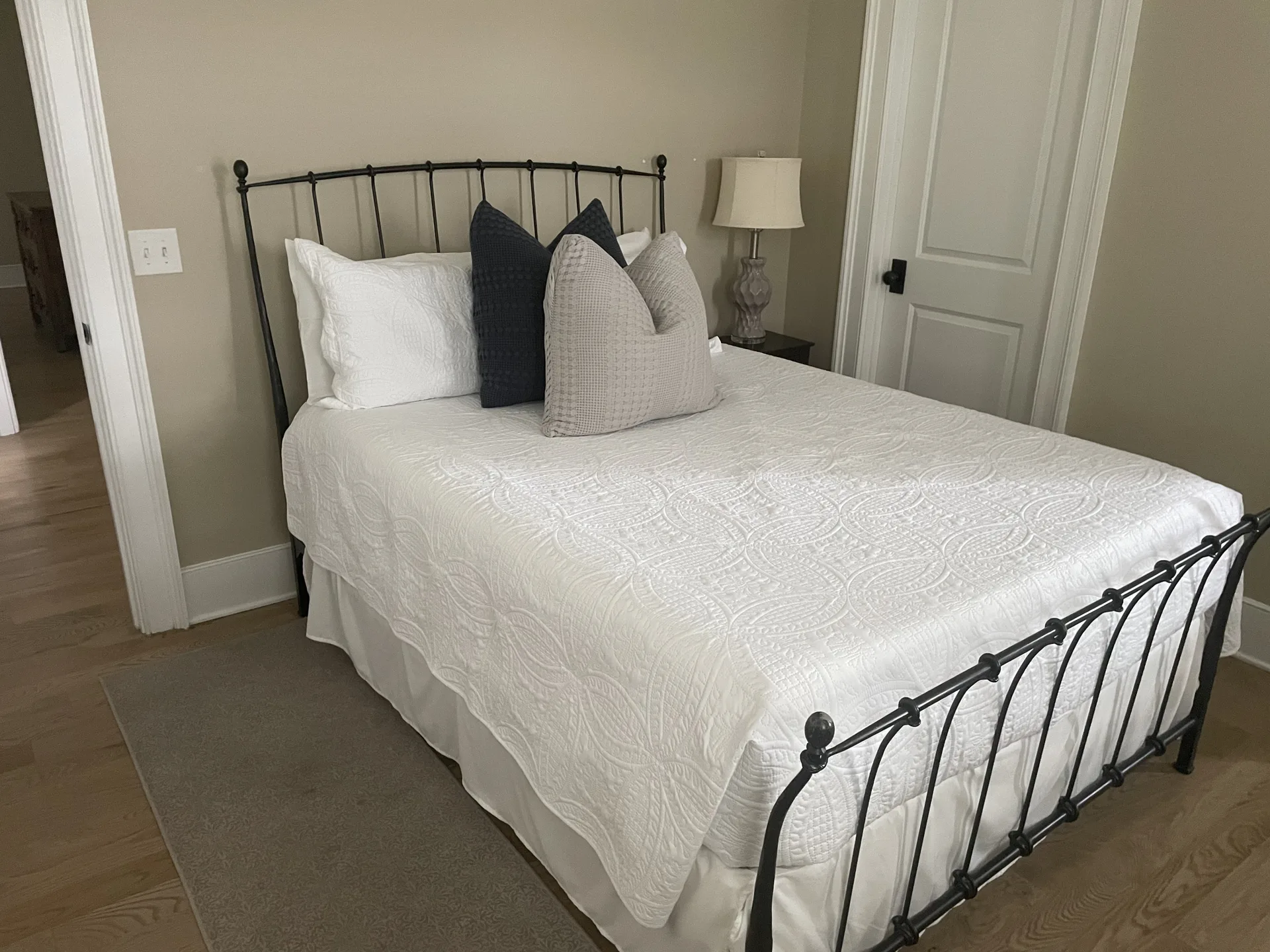 Queen bedroom with iron bed, white linens, and wide-plank hardwood floors