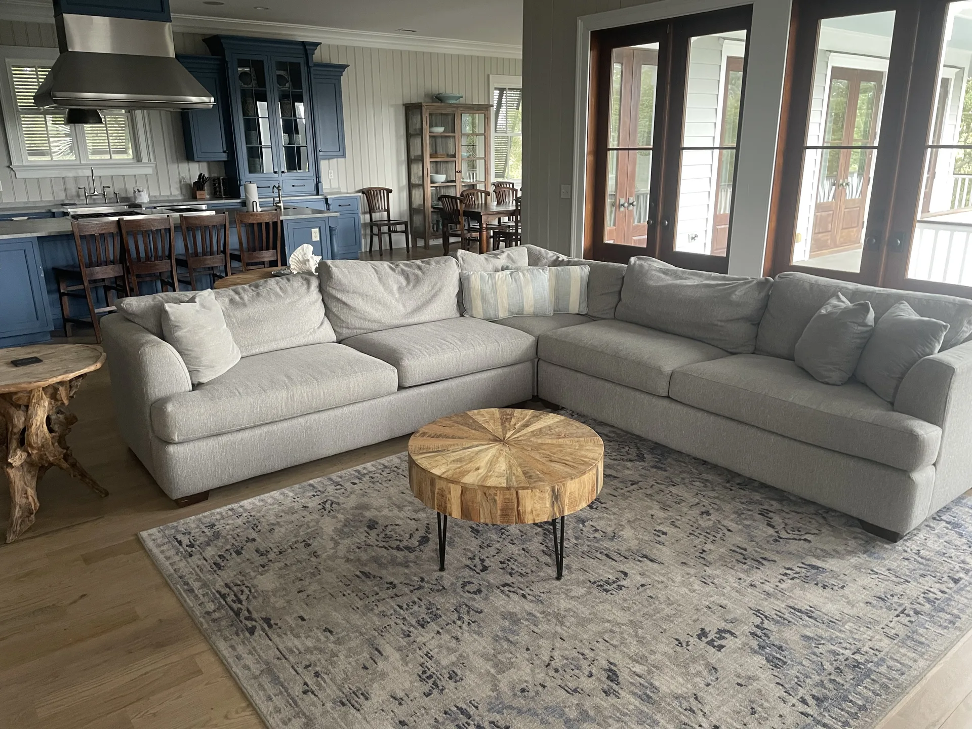 Open-plan living area with gray sectional, round coffee table, and French doors