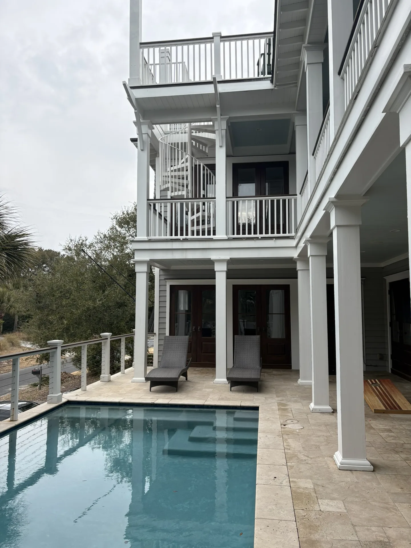 Pool side view with palm trees and covered porch in background