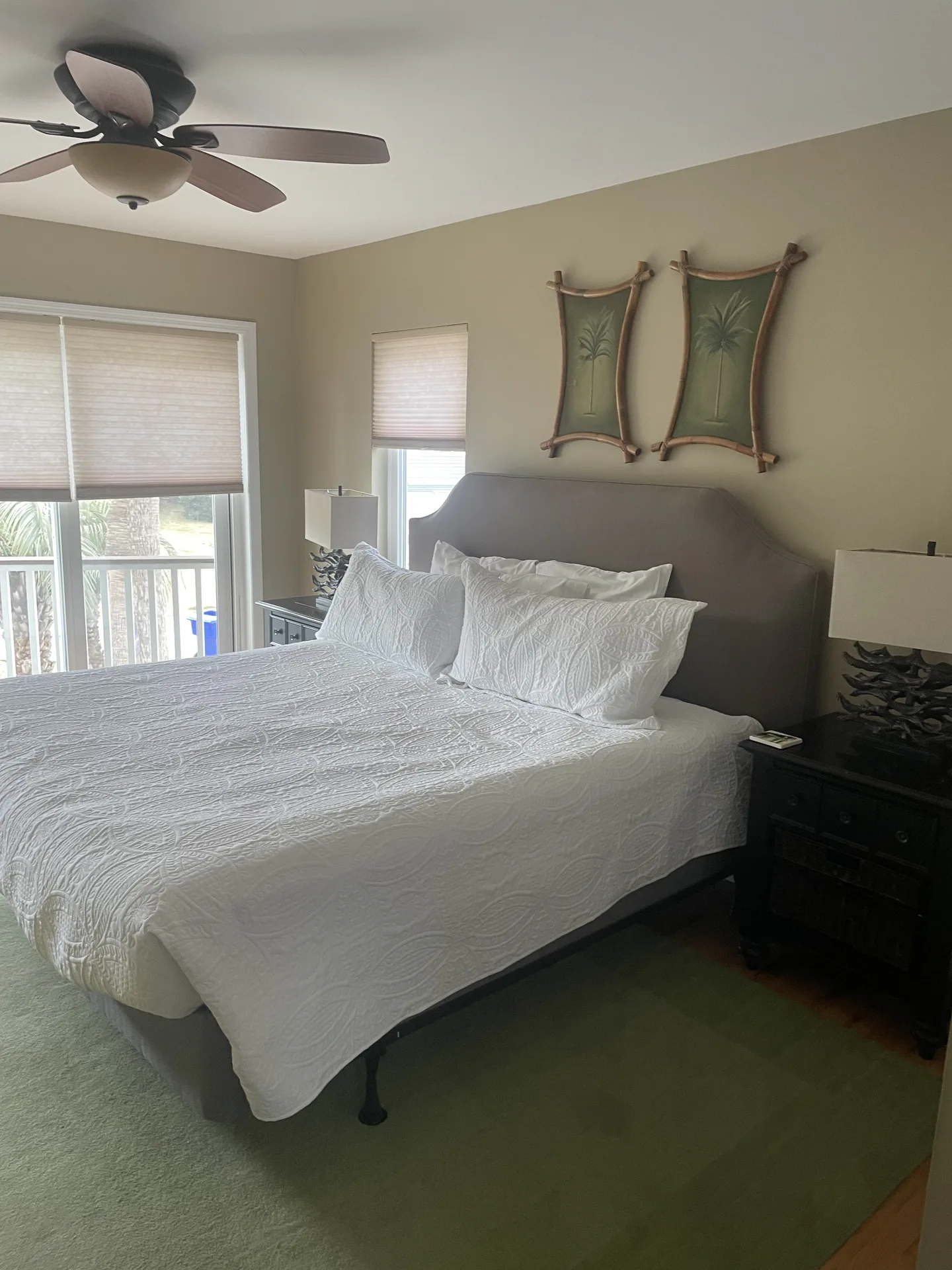 Master bedroom with king bed, palm tree wall decor, and balcony access