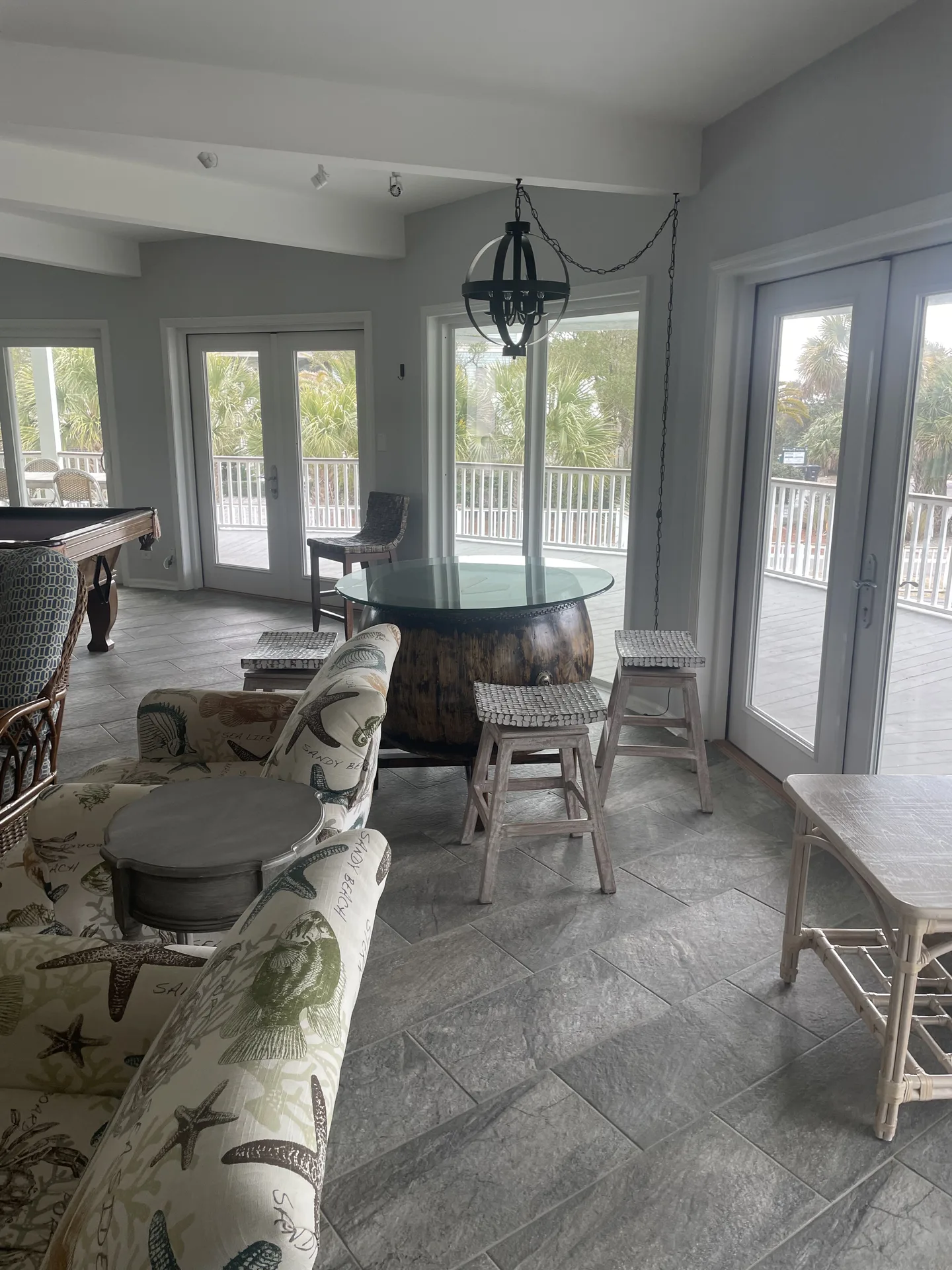 Dining area with barrel base glass table, pool table, and wraparound porch views