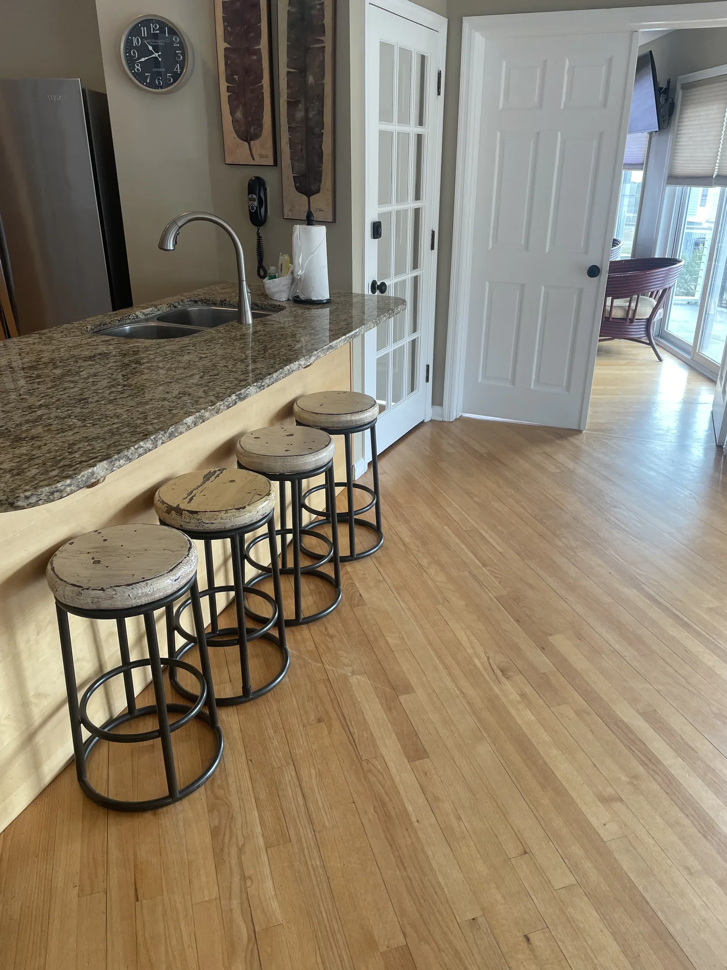Granite kitchen island with four industrial bar stools and stainless appliances
