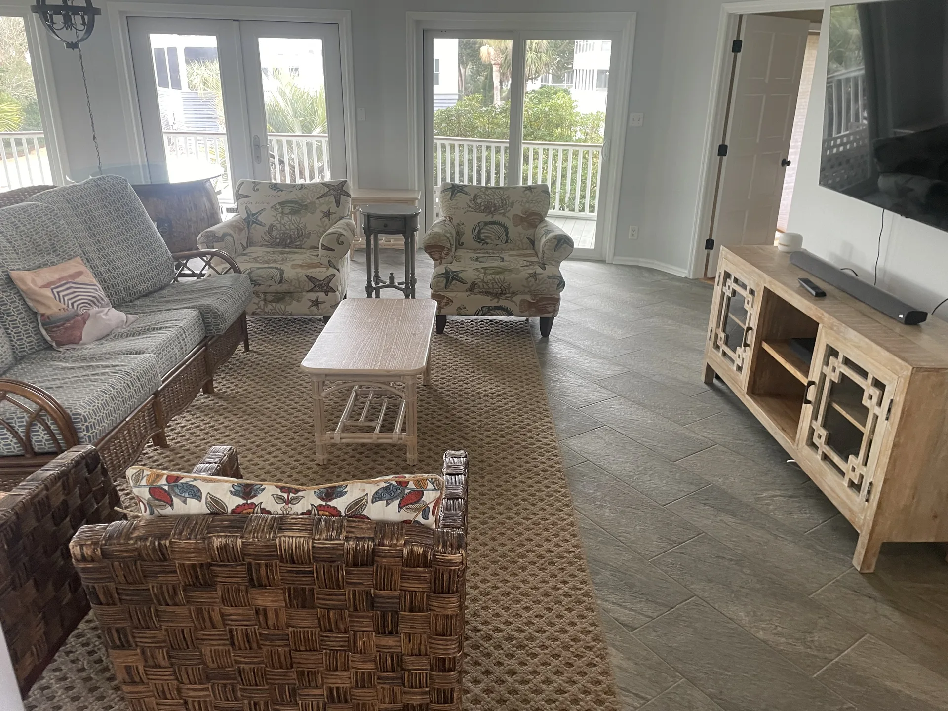 Spacious living room with coastal decor, wicker furniture, and natural light